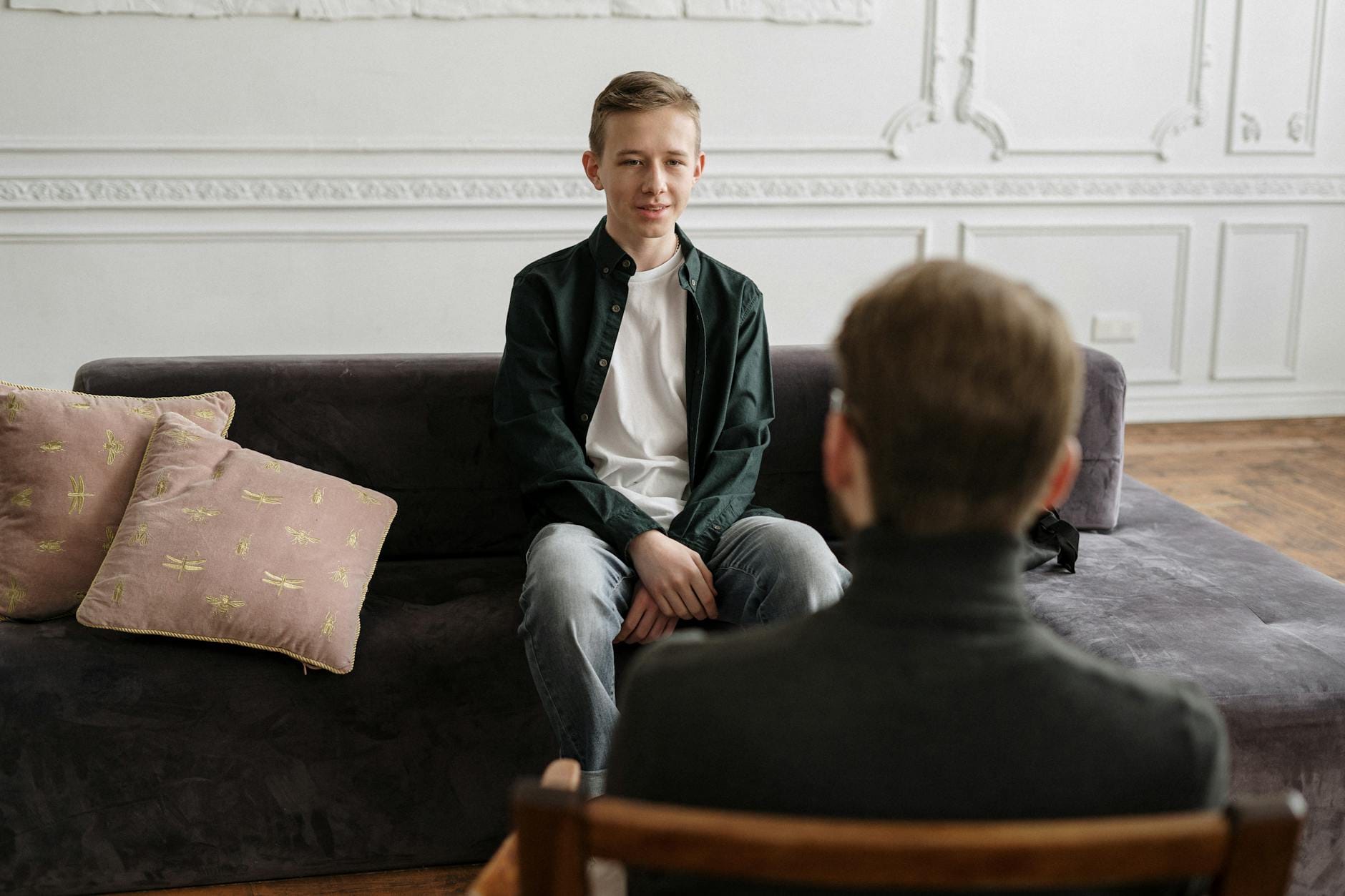 Nastolatek rozmawia z psychologiem na kanapie w nowoczesnym gabinecie