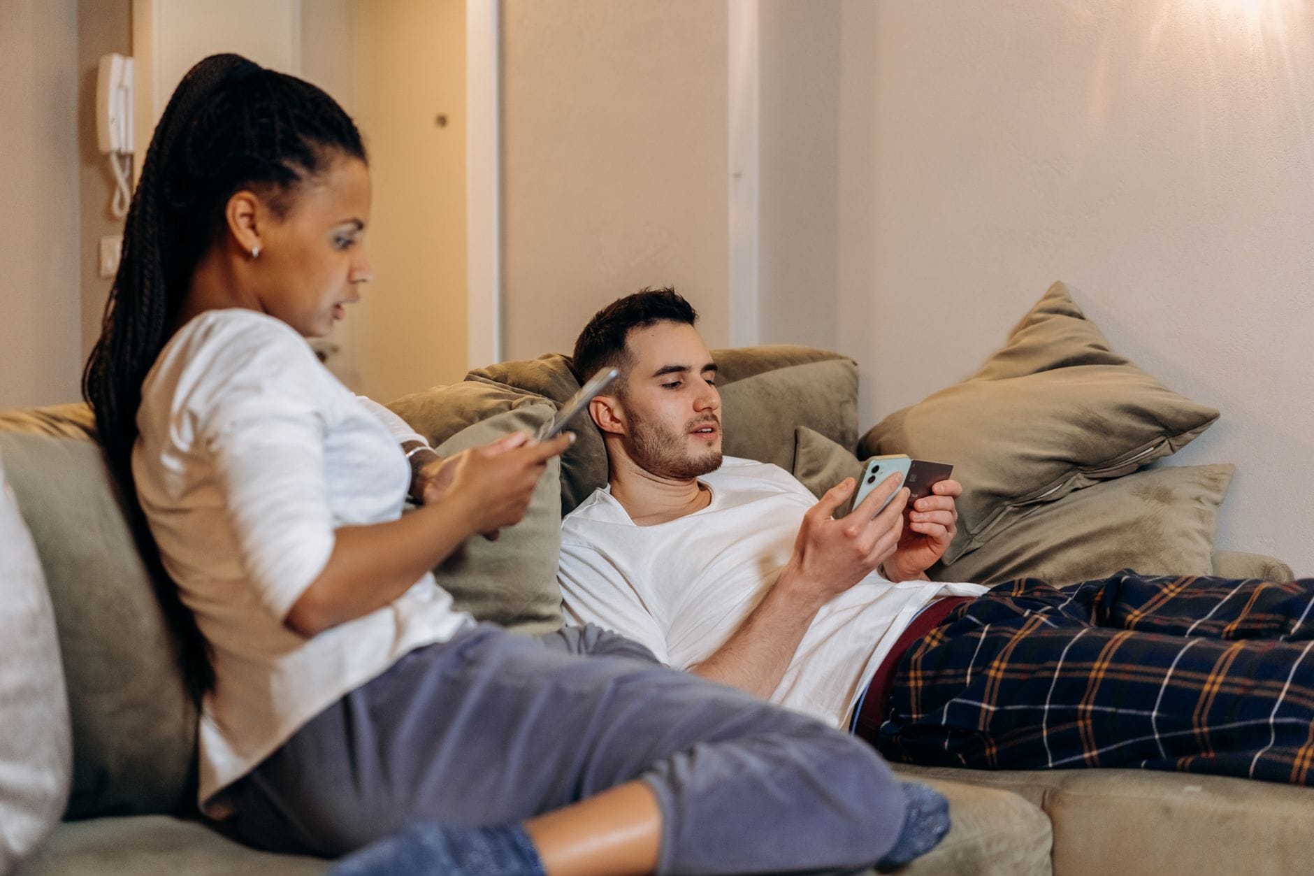 Para na kanapie korzysta ze smartfonów i karty do zakupów online
