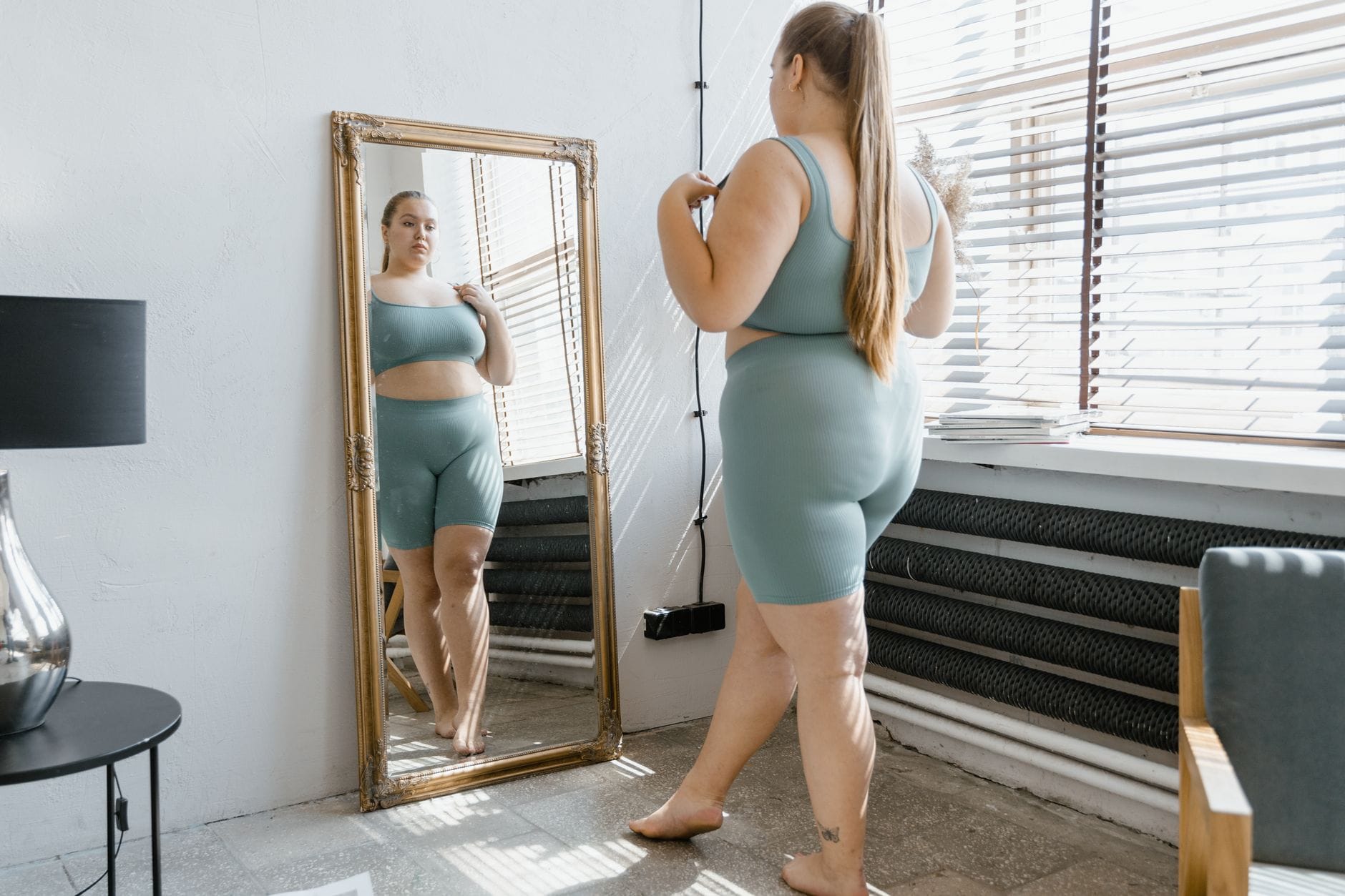 Kobieta plus size w stroju sportowym podziwia odbicie w lustrze