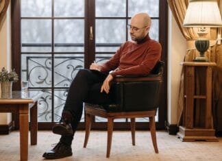 Kryzys zawodowy: zmienić pracę, odpocząć czy skorzystać z terapii? Łysy mężczyzna zapisujący notatki w fotelu przy oknie
